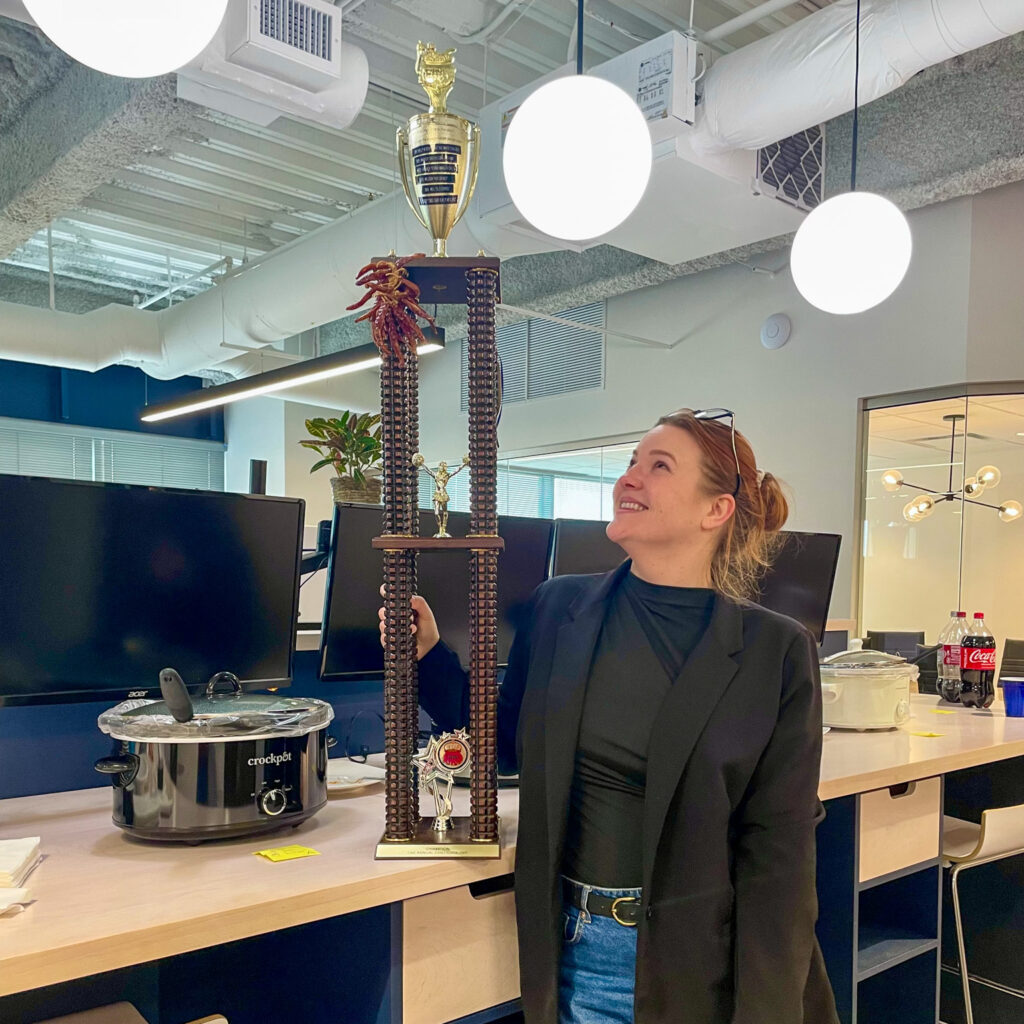 Emily proudly holding the chili cookoff trophy at D and E Inc. office.