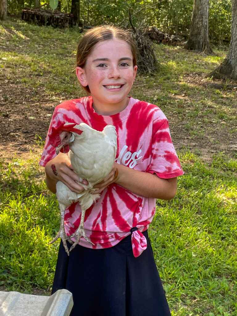 Young girl holding a chicken.