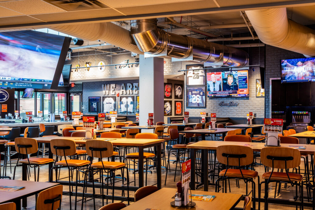 Large wall mural depicting a vibrant college football stadium, enhancing the sports-themed interior design.